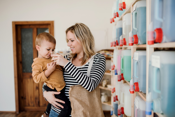 An attractive young woman with a toddler boy buying liquids in zero waste shop.