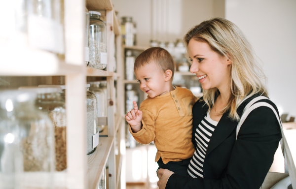 An attractive young woman with a toddler boy buying groceries in zero waste shop.