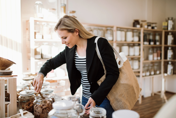 An attractive young happy woman buying groceries in zero waste shop.