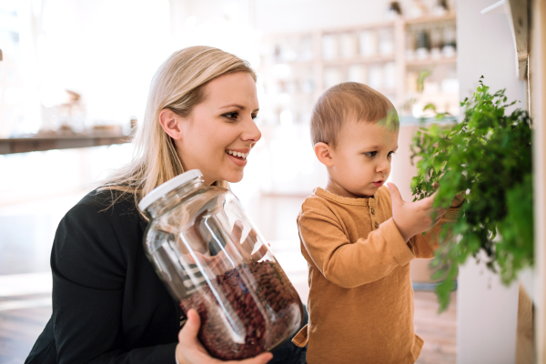 An attractive young woman with a toddler boy buying groceries in zero waste shop.