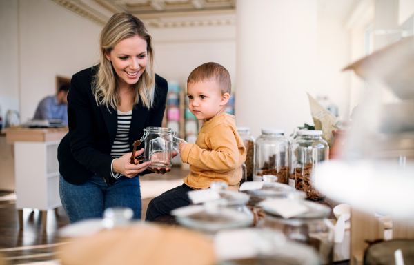 An attractive young woman with a toddler boy buying groceries in zero waste shop.