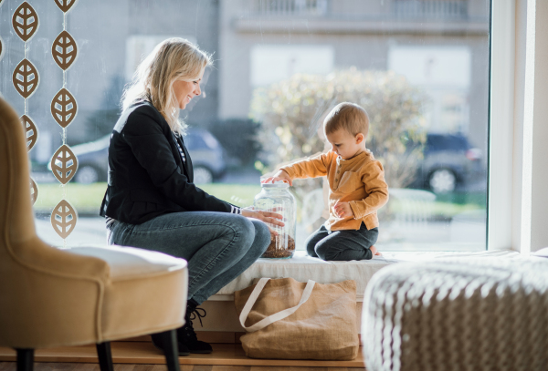 An attractive young woman with a toddler boy buying groceries in zero waste shop, resting.