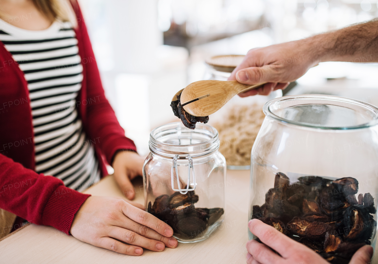 A midsection of unrecognizable shop assistant serving a customer in a zero waste shop.