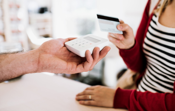 A midsection of customer and shop assistant making wireless or contactless payment using credit card in a shop.