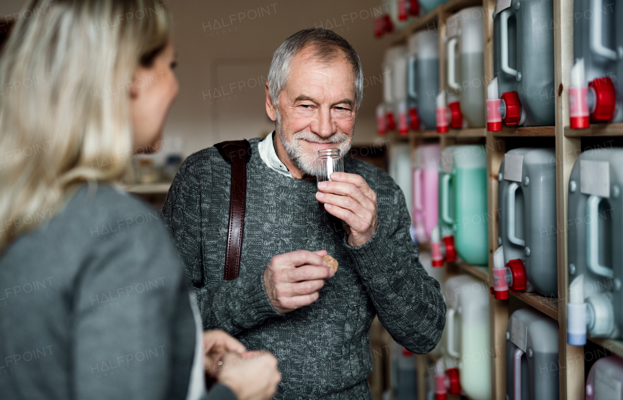 Young female shop assistant serving a senior man customer in a zero waste shop.