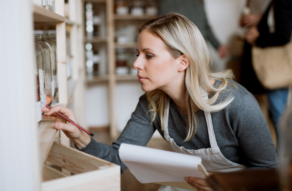 A female shop assistant working in a zero-waste shop, checking stock.