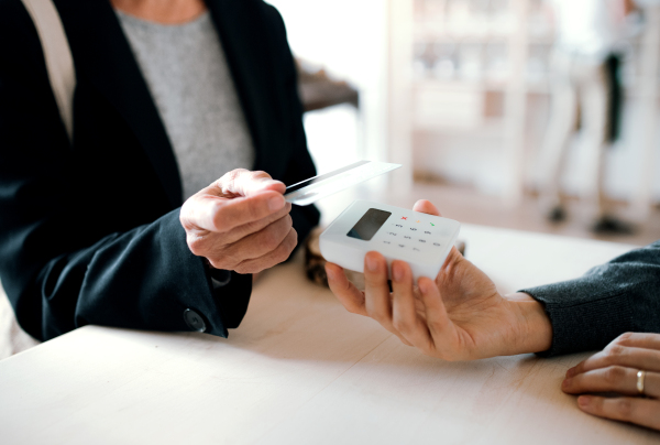 A midsection of unrecognizable customer and shop assistant making contactless payment in a shop.