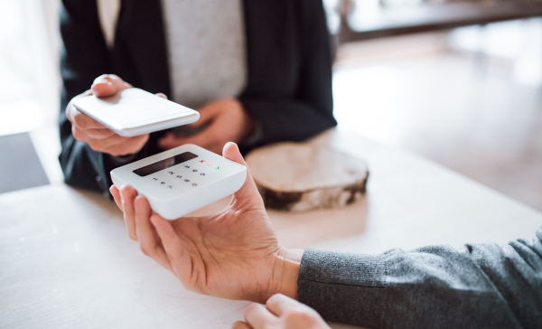 A midsection of unrecognizable customer and shop assistant making mobile payment in a shop.