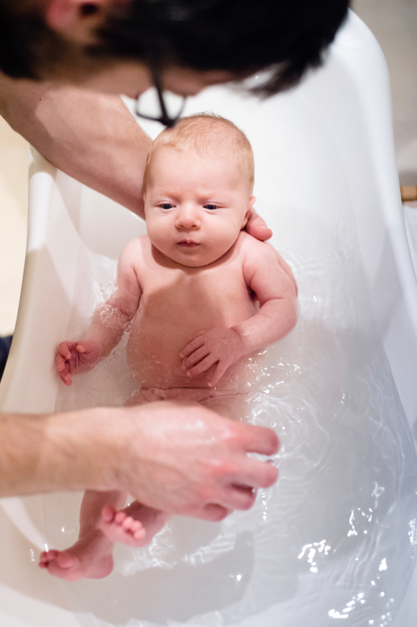 Close up of unrecognizable young father bathing his little baby son