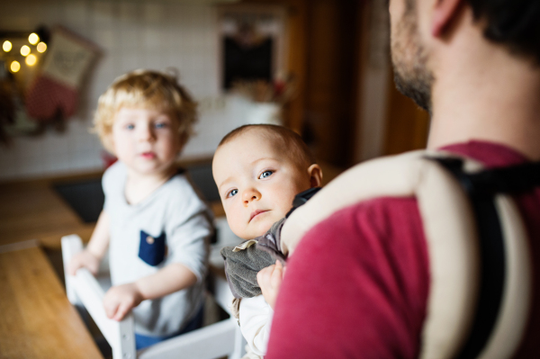 Unrecognizable father with two toddlers at home. Paternity leave.