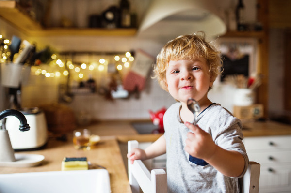 A cute toddler boy washing up the dishes.