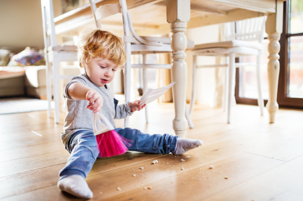 A cute toddler boy with brush and dustpan at home.