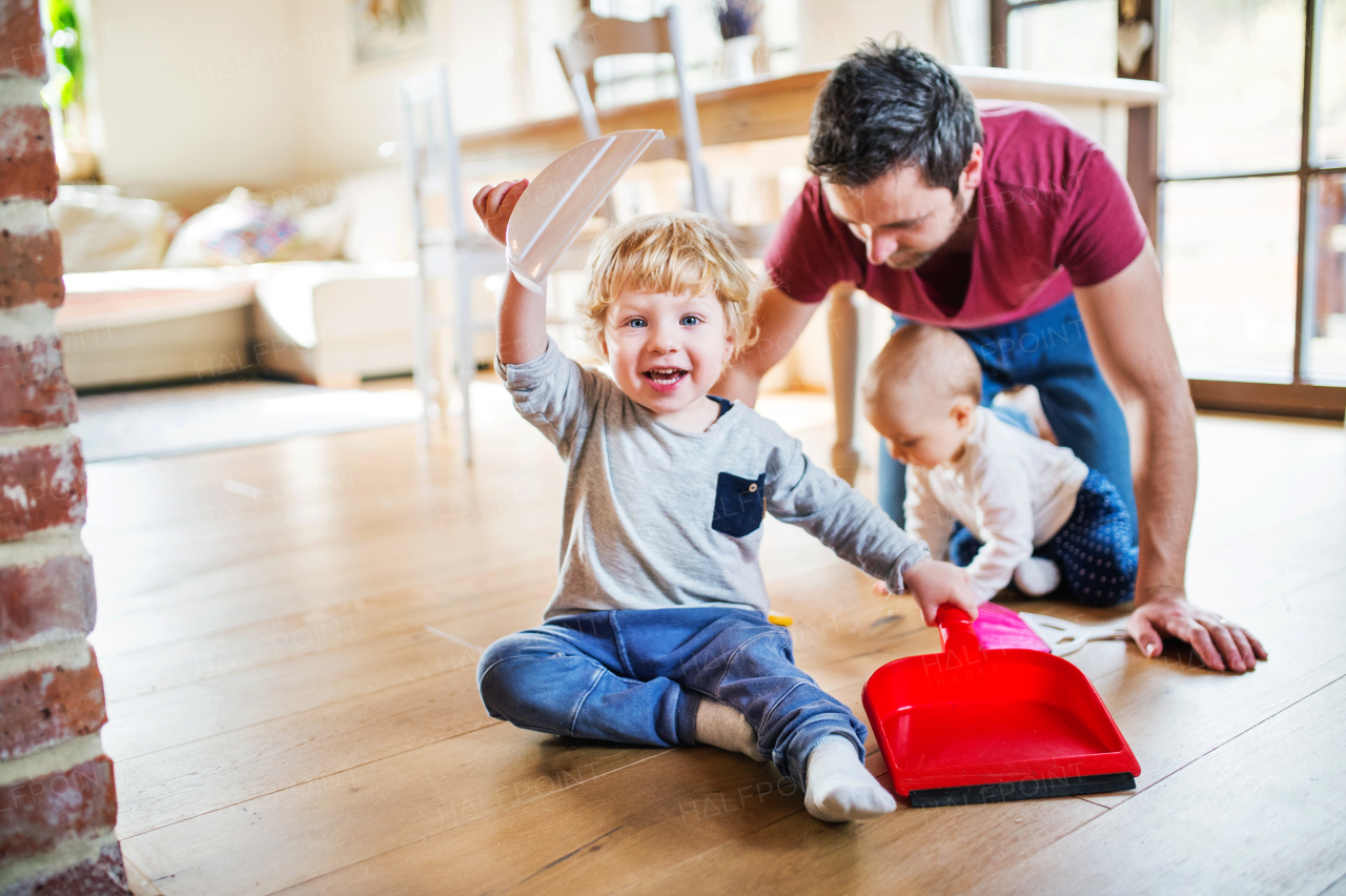 Father and two toddlers with brush and dustpan. Paternity leave.