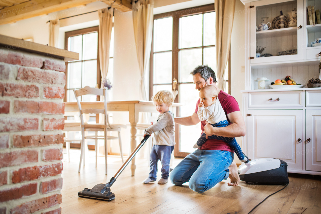 Father and two toddlers doing housework. Paternity leave.