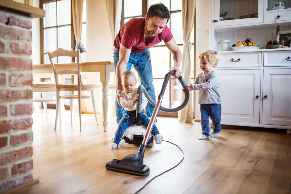 Father and two toddlers doing housework. Paternity leave.