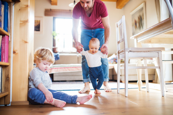 Father with two toddlers at home. First steps. Paternity leave.