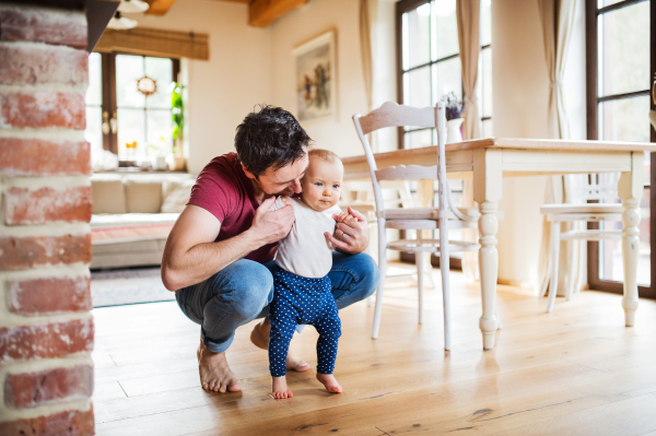 Father with a baby girl at home. Paternity leave.