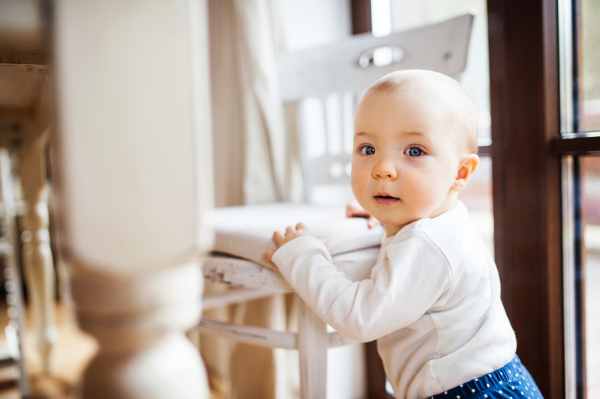 A cute toddler girl standing at the table at home.