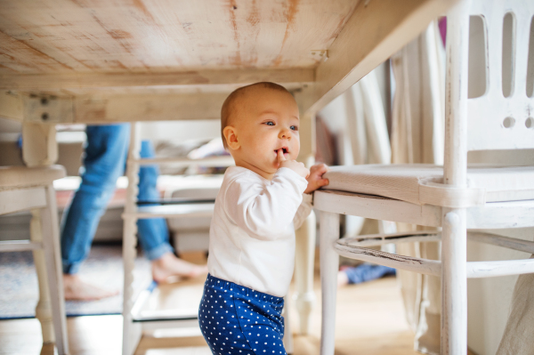 A baby girl under the table at home. Paternity leave.