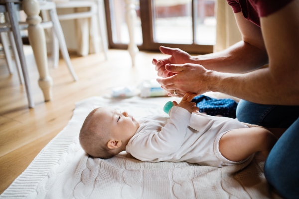 Unrecognizable father with a baby girl at home. Paternity leave.