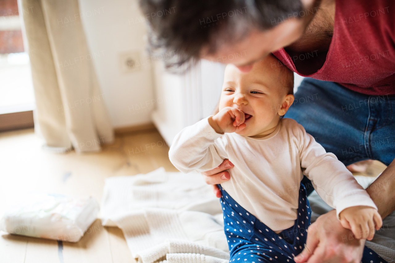 Unrecognizable father with a baby girl at home. Paternity leave.