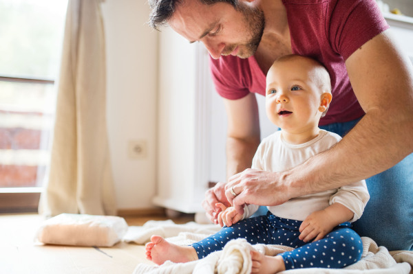 Handsome father with a baby girl at home. Paternity leave.