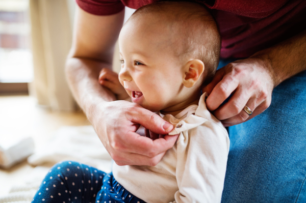 Unrecognizable father with a baby girl at home. Paternity leave.