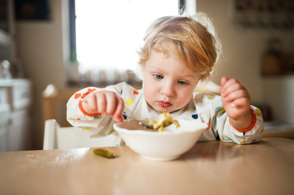 A cute toddler boy eating at home.