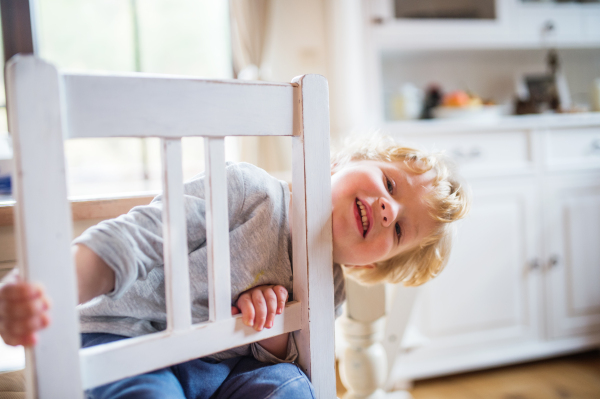 A toddler boy sitting on the chair at home, having fun.