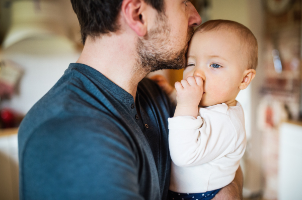 Unrecognizable father with a baby girl at home. Paternity leave.