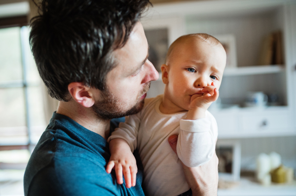 Af ather with a baby girl at home. Paternity leave. Thumb sucking.