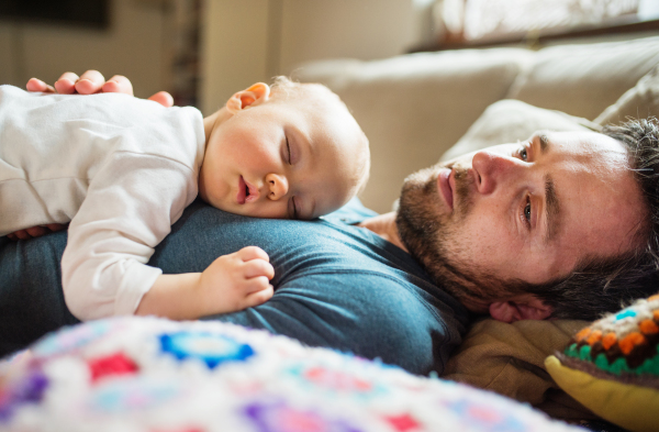 Father with a baby girl at home, sleeping on the sofa. Paternity leave. Close up.