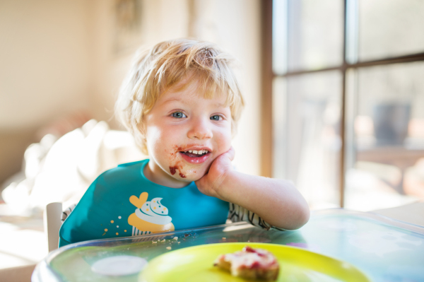 A cute toddler boy eating at home.