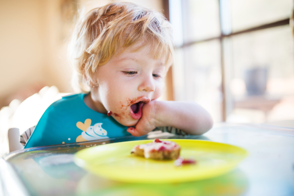 A cute toddler boy eating at home.