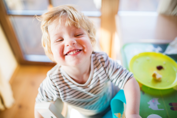 A cute toddler boy eating at home.