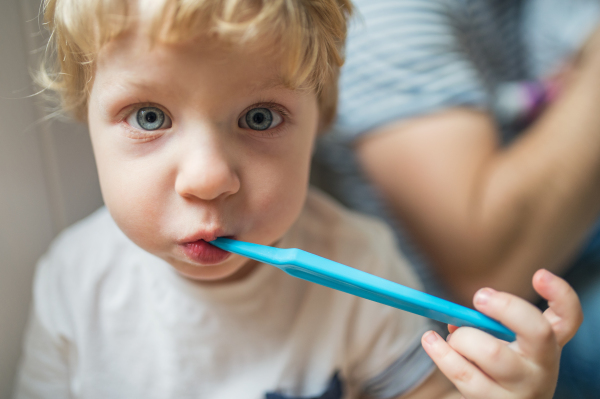 A happy toddler boy brushing his teeth at home. Close up. Paternity leave.