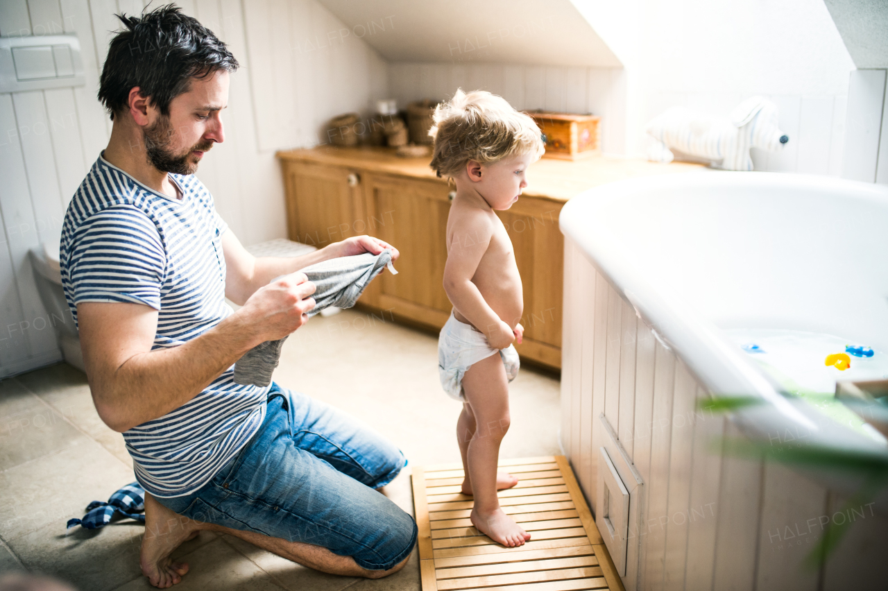 Father with a toddler child at home, getting ready for a bath. Paternity leave.