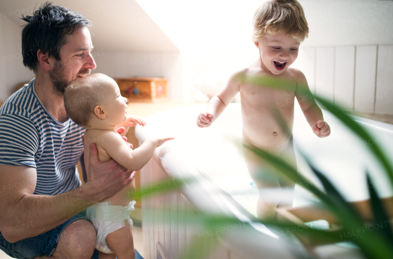 Father washing two toddlers in the bath in the bathroom at home. Paternity leave.