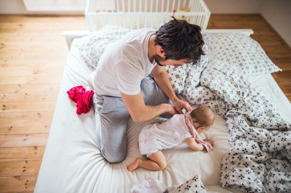 Father with a toddler girl on bed at home at bedtime. Paternity leave.