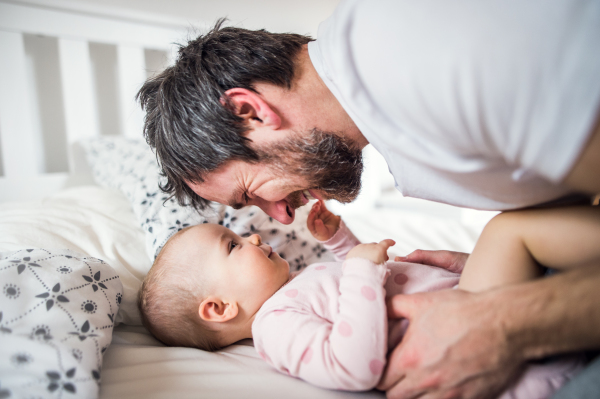 Father with a toddler girl on bed at home at bedtime. Paternity leave.