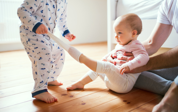 Unrecognizable father and toddler children sitting on the floor at home at bedtime. Paternity leave.