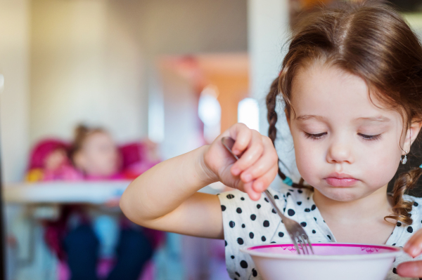 Cute little girl in the kitchen smiling, eating spaghetti