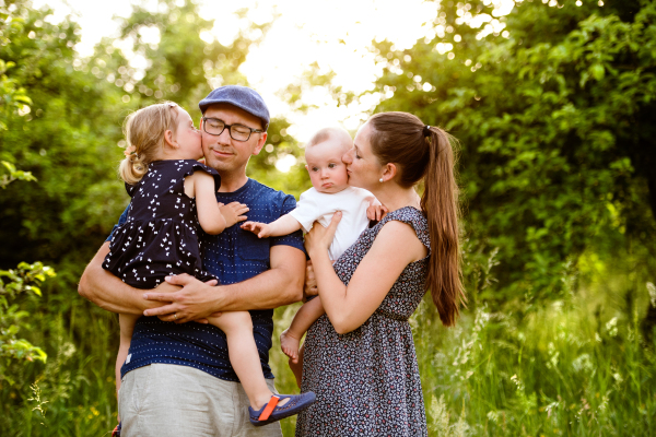 Happy young family with little children spending time together outside in green summer nature