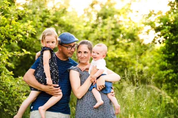 Happy young family with little children spending time together outside in green summer nature