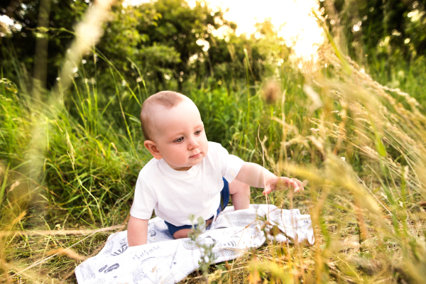 Cute little baby boy outside in in green sunny summer nature