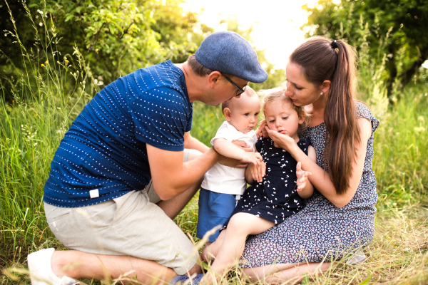 Happy young family with little children spending time together outside in green summer nature