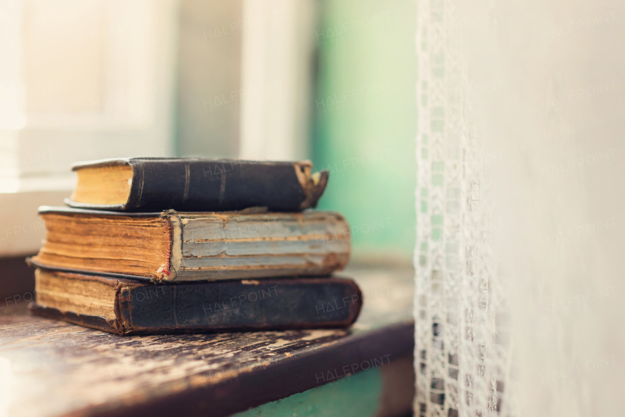 Stack of old books laid on windowsill