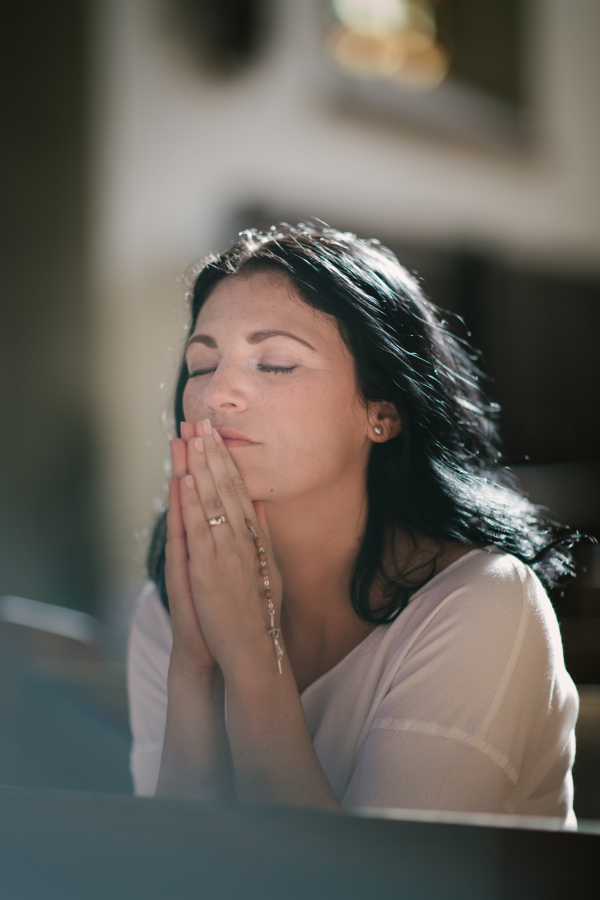 Beautiful woman with a rosary praying in the church