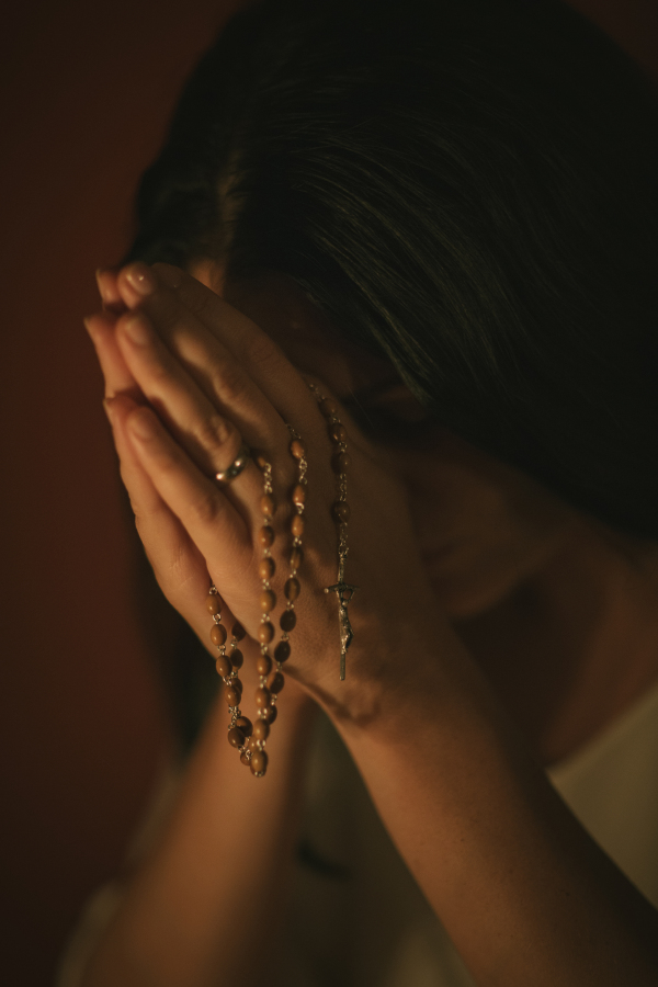 Unrecognizable woman with a rosary praying in the church