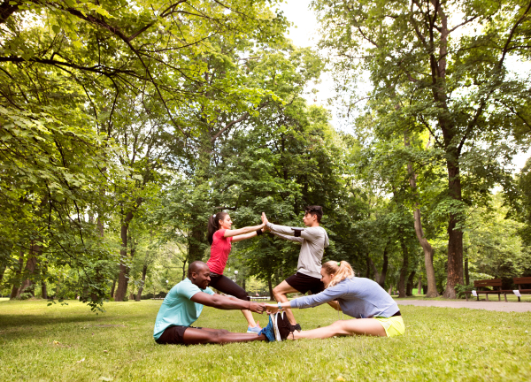 Group of young runners in nature warming up and stretching